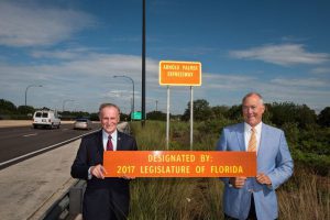 Florida Representative Mike Miller and Senator David Simmons hold the dedication sign for the Arnold Palmer Expressway designated by 2017 Legislature of Florida.